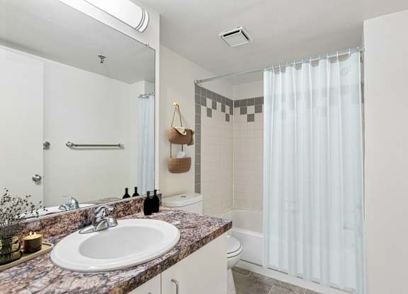 A bathroom with a marble countertop and a white sink.