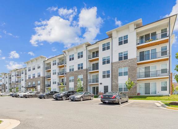 A row of modern apartment buildings with cars parked in front.