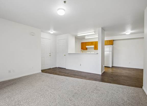 A large empty room with white walls and a grey carpet.