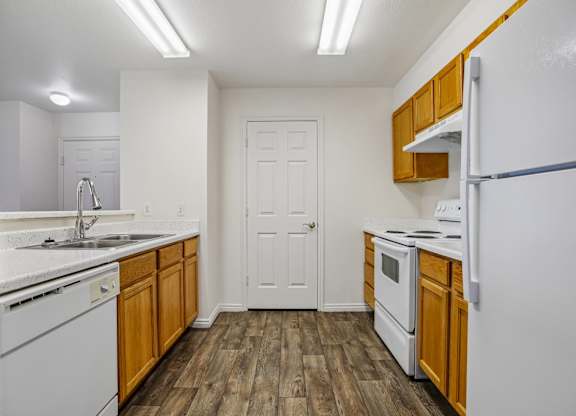 A kitchen with white appliances and wooden cabinets.