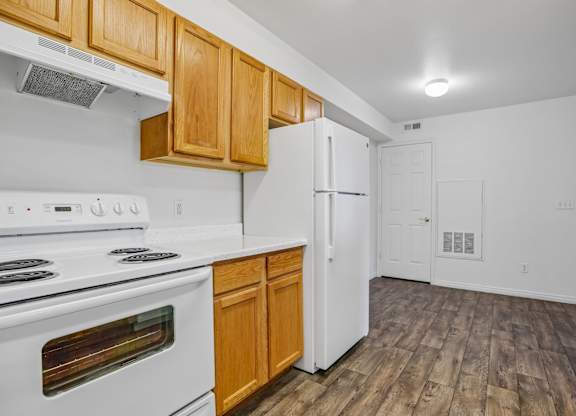 A kitchen with white appliances and wooden cabinets.