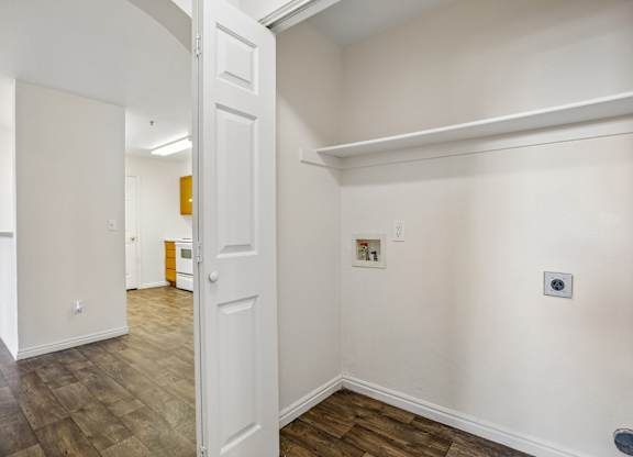 A white door is open to a hallway with wood floors.