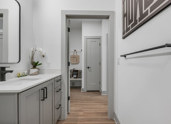 a bathroom with a sink and a mirror and a hallway to a closet