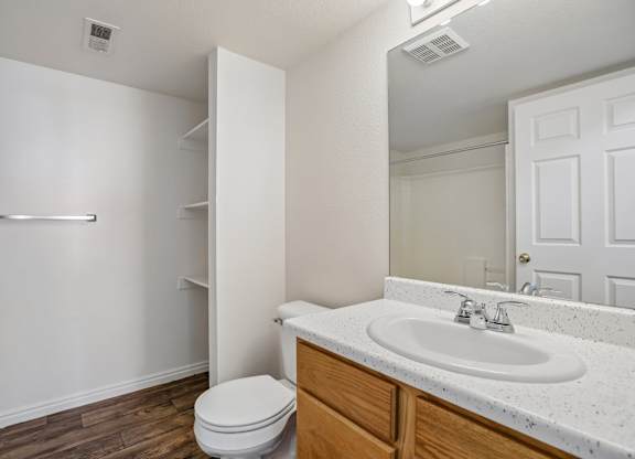 A white bathroom with a toilet, sink, and mirror.