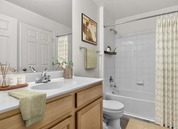 A bathroom with a white toilet, a sink with a green towel on it, and a shower with a white curtain.