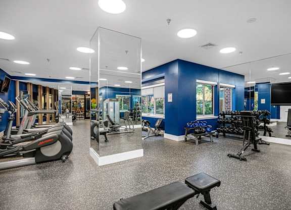 A gym with a variety of equipment including treadmills, weights, and exercise machines.
