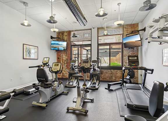 A gym with a brick wall and a row of treadmills.