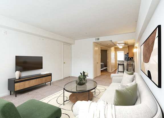 A living room with a white couch, a green chair, and a glass coffee table at The Fields of Bethesda, Chevy Chase, MD