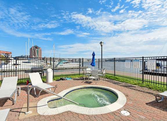 A hot tub sits on a brick patio with chairs around it.