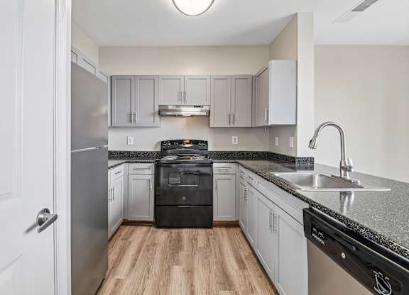 A kitchen with a black dishwasher and stove top oven.