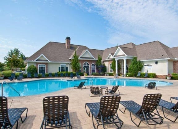 a swimming pool with chairs around it in front of a house at Alexander Ridge Apartments, Canton , Georgia