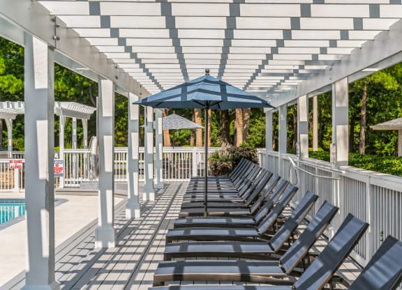 a row of lounge chairs under a white covered pavilion with an umbrella at St. Andrews Reserve, Wilmington, NC, 28412