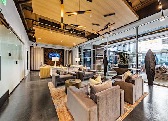 the lobby of a building with couches and chairs and a tv at South and Hollis, Charlotte