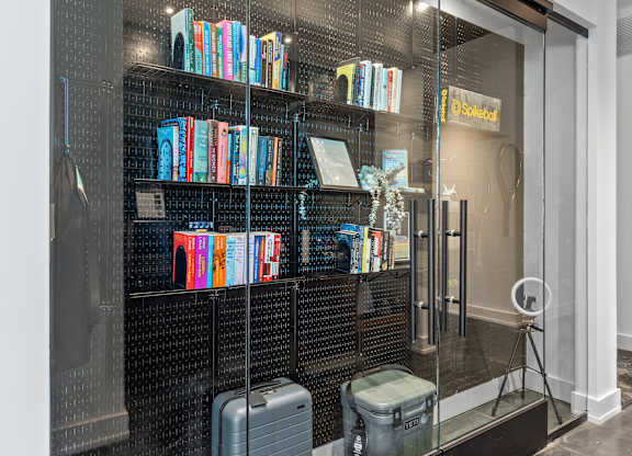 a library with a glass wall and shelves with books and luggage  at South and Hollis, Charlotte