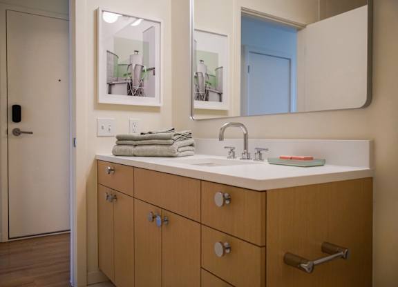 A bathroom with a sink, mirror, and cabinets.