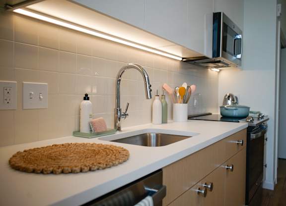 A kitchen with a white counter top and a stainless steel faucet.