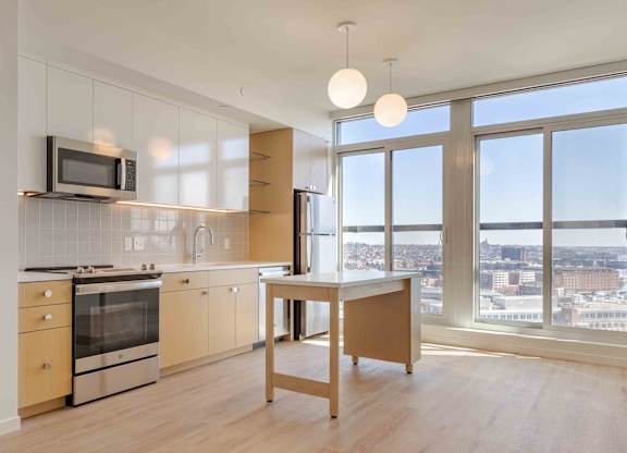 A kitchen with a microwave above the stove and a table in front of a window.