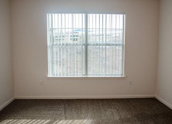 A room with a window and a carpeted floor at Arrowhead Ridge Apartments, Rio Rancho, NM