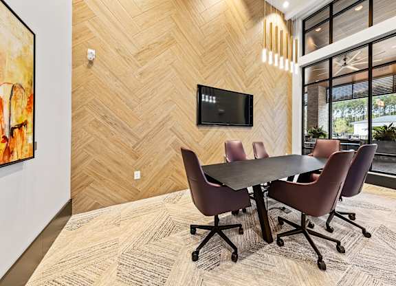 A conference room with a table and chairs and a TV on the wall at Preston Ridge Apartments.