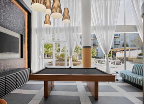 A billiard table is in the middle of a room with a fireplace and a couch.