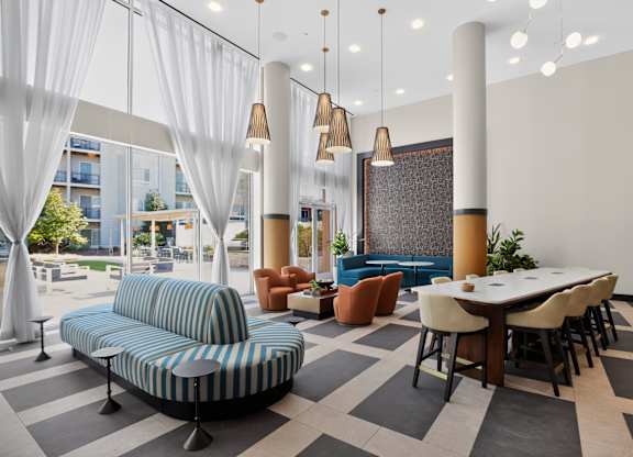 A modern living room with a blue striped sofa and a dining table with chairs.