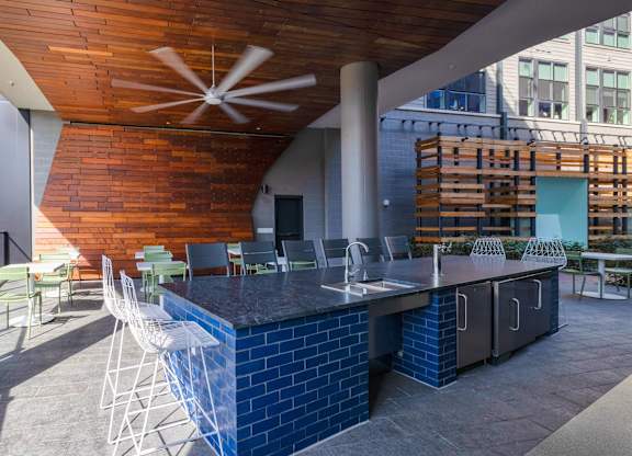 a patio with a bar and chairs and a building in the background at The Chase at Bryant Street, Washington