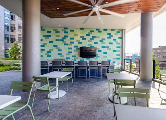 a patio with tables and chairs and a wall with a television at Coda at Bryant Street, Washington