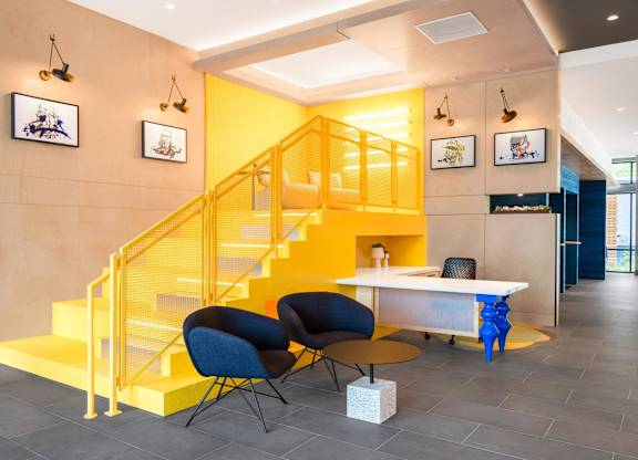 a yellow staircase in a lobby with chairs and a table at Coda at Bryant Street, Washington DC