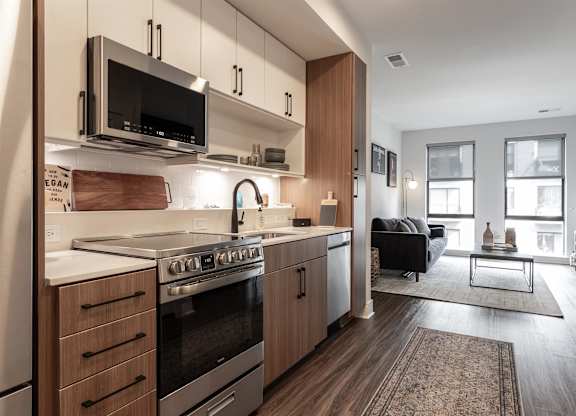 a kitchen with wooden cabinets and a stove and a microwave at Coda at Bryant Street, Washington, 20002