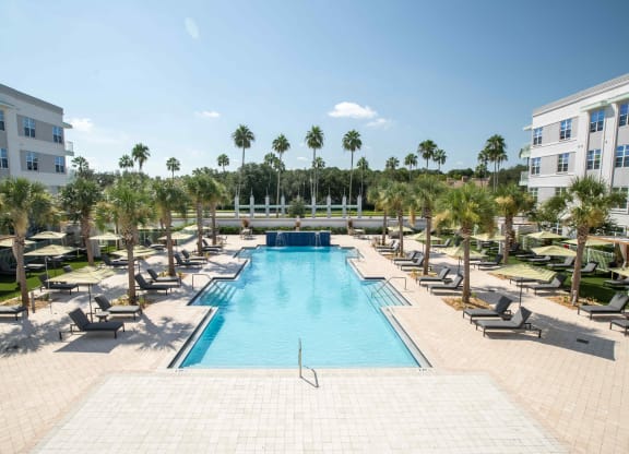 a swimming pool with chaise lounge chairs and palm trees in the background at Delamarre at Celebration, Celebration