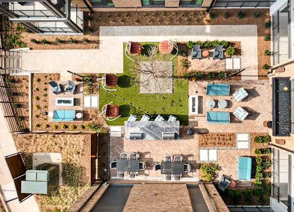 A patio with a table surrounded by chairs and a lawn at Hawkins Press Apartments, Charlotte, 28203