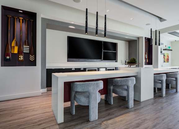 A modern kitchen with a white countertop and grey chairs.
