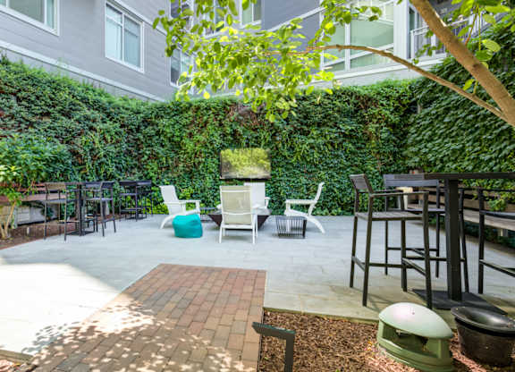 A patio with a white table and chairs surrounded by a green wall.