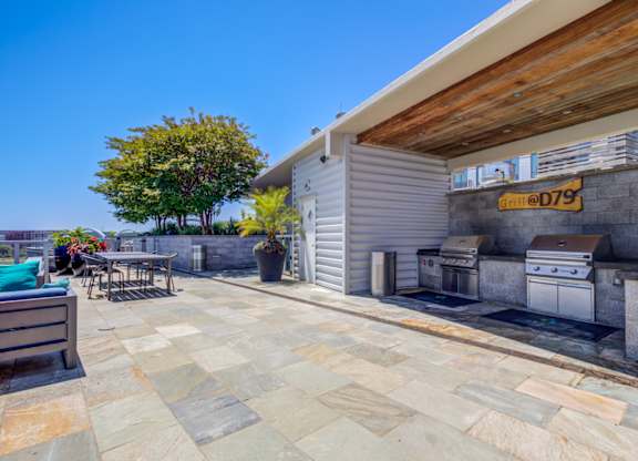 A patio with a grill and a table with chairs.