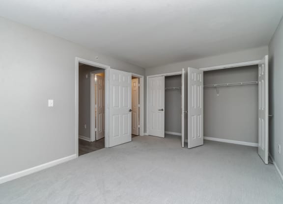 an empty bedroom with three closets and three doors