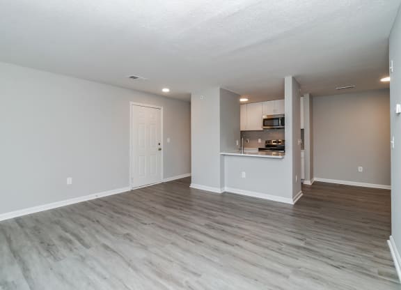 the living room and kitchen of an apartment with wood flooring at The Fields at Lorton Station, Virginia