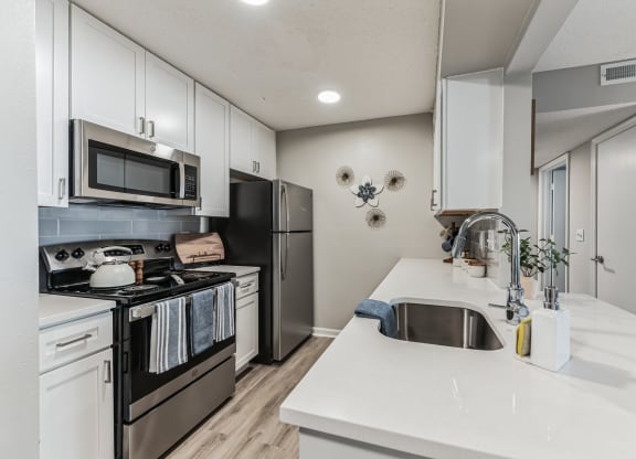 a kitchen with white cabinets and stainless steel appliances at Brampton Moors, Cary, 27513