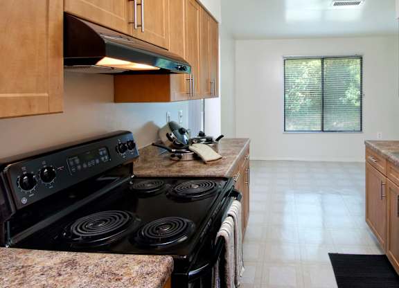 A kitchen with a black stove top oven and wooden cabinets.