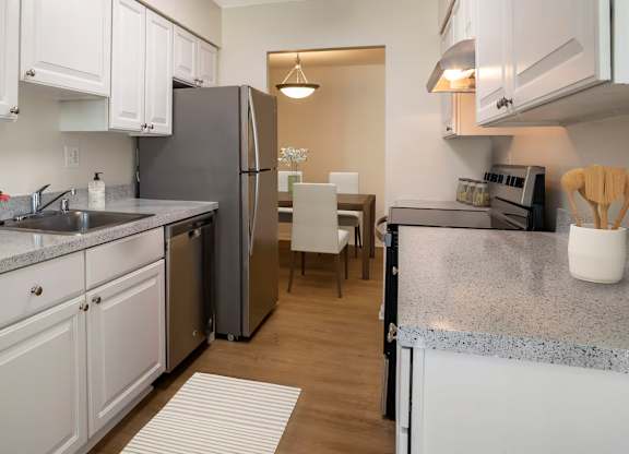 A kitchen with white cabinets and a grey granite countertop.
