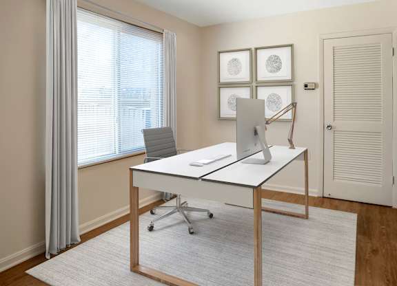 A white desk with a laptop and a phone on it in a room.