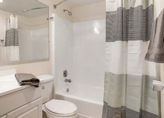 A white bathroom with a toilet, sink, and shower.