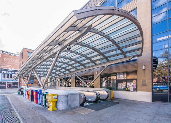 A row of colorful trash cans are lined up outside a building.