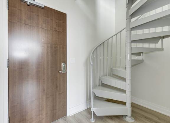 A white spiral staircase with a wooden door.