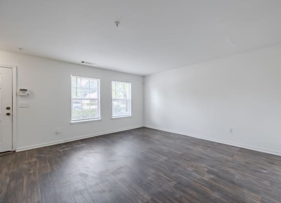 an empty living room with wood floors and white walls at Greens at Stonecreek, Lithonia, 30038
