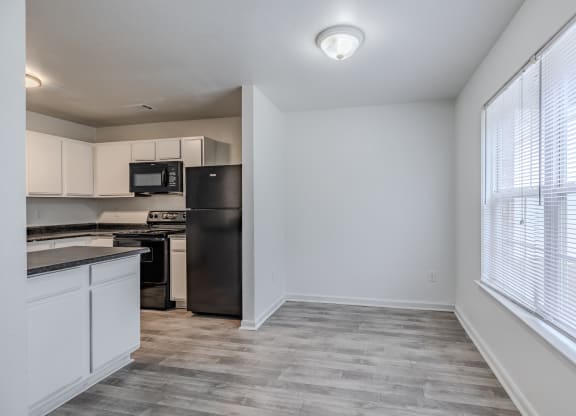 an empty kitchen with white cabinets and a black refrigerator and at Greens at Stonecreek, Lithonia
