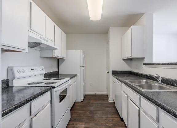 a kitchen with white cabinets and white appliances and granite counter tops at Greens at Stonecreek, Lithonia, 30038