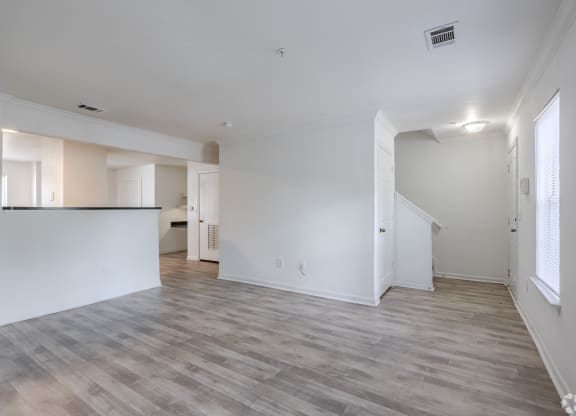 an empty living room and kitchen with white walls and wood flooring at Greens at Stonecreek, Lithonia, Georgia