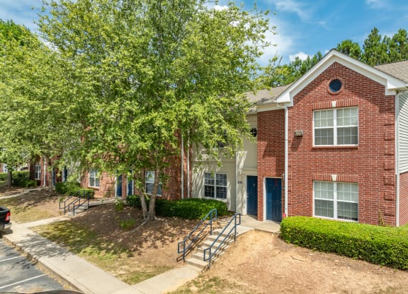 our apartments offer a spacious courtyard with trees and a brick building at Greens at Stonecreek, Lithonia, Georgia