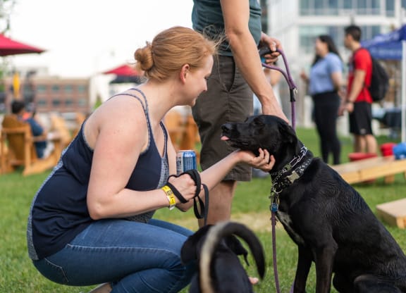 a woman petting a black dog on a leash at Allied Harbor Point, Maryland