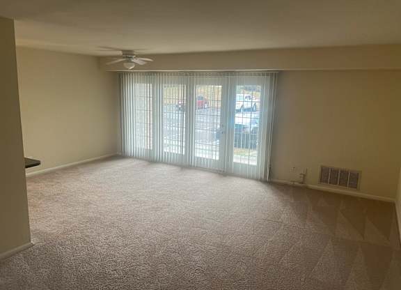 A room with a carpeted floor, a ceiling fan, and a sliding glass door at Shenandoah Station Apartments, Virginia 22172